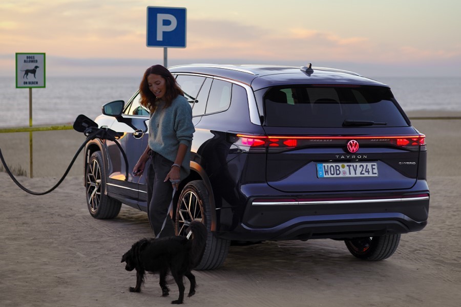 VW Tayron beim Laden am Strand mit einer Frau und einem Hund